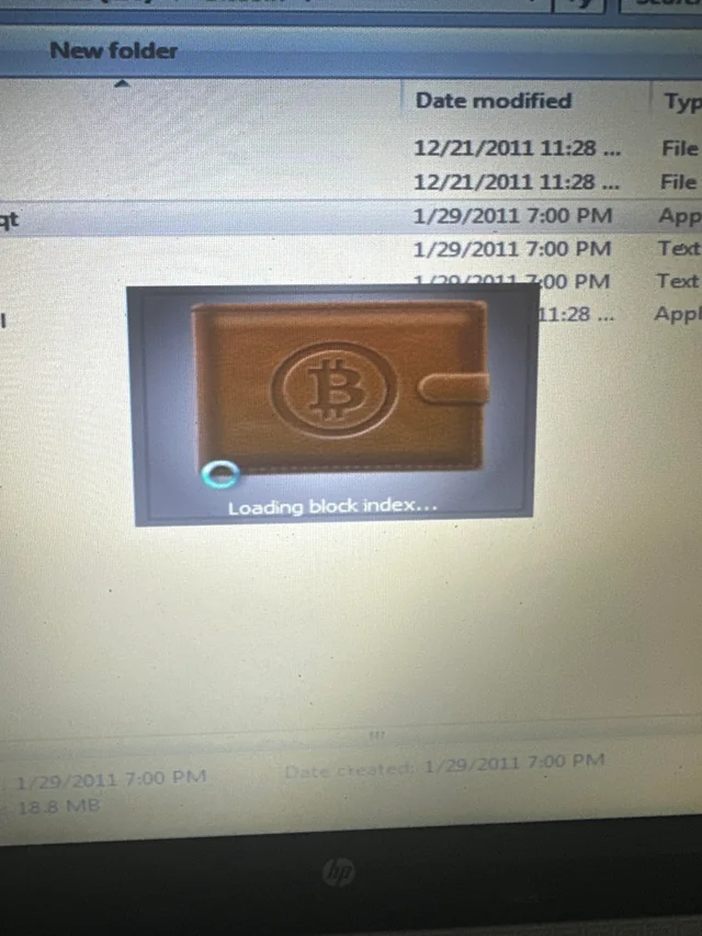 A photo of a vintage Bitcoin-Qt wallet interface on a computer screen, displaying a leather wallet icon and the text 'Loading block index...' with folder timestamps from January 2011. A classic example of bitcoin nostalgia.